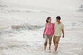 Young couple smiling and walking by the waters edge on the beach, China