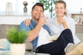 young couple on sofa at home laughing and eating popcorn Royalty Free Stock Photo