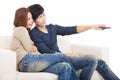 Young couple on sofa watching TV with remote control Royalty Free Stock Photo