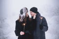 Young couple with sparklers in winter forest. Smiling family with bengal lights. Royalty Free Stock Photo