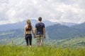 Young couple, sportive man and slim woman holding hands outdoors on background of beautiful mountain landscape on sunny summer day Royalty Free Stock Photo