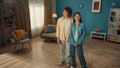 A young couple is standing in a cozy living room and examining it. The curlyhaired young man put his arm around the Royalty Free Stock Photo