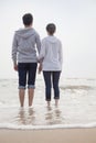 Young couple standing and holding hands on the beach and looking out to sea Royalty Free Stock Photo
