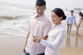 Young couple standing and looking at seashell on the beach, China Royalty Free Stock Photo