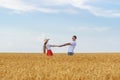 Young couple standing in middle of wheat field and holding hands. Romance of countryside Royalty Free Stock Photo