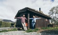 Young couple standing next to the rental wooden cottage in Jotunheimen park, Norway