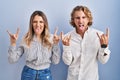 Young couple standing over blue background shouting with crazy expression doing rock symbol with hands up Royalty Free Stock Photo