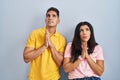 Young couple standing over isolated background begging and praying with hands together with hope expression on face very emotional Royalty Free Stock Photo