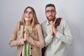 Young couple standing over white background begging and praying with hands together with hope expression on face very emotional Royalty Free Stock Photo