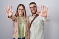 Young couple standing over white background showing and pointing up with fingers number ten while smiling confident and happy Royalty Free Stock Photo