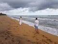Young couple standing on the sandy beach of a tropical ocean opposite each other Royalty Free Stock Photo