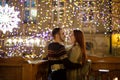 Young couple stands embracing against the shining festive garlands.