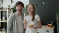 Young couple stared at the camera, standing in surprise in the kitchen at home