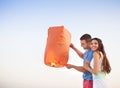 Young couple start a red Chinese sky lantern