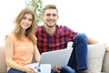 Young couple of students uses a laptop sitting on sofa Royalty Free Stock Photo