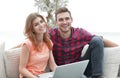 Young couple of students uses a laptop sitting on sofa Royalty Free Stock Photo