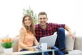 Young couple of students uses a laptop sitting on sofa Royalty Free Stock Photo