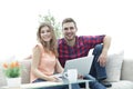 Young couple of students uses a laptop sitting on sofa Royalty Free Stock Photo