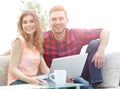 Young couple of students uses a laptop sitting on sofa Royalty Free Stock Photo