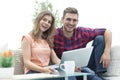 Young couple of students uses a laptop sitting on sofa Royalty Free Stock Photo