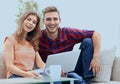 Young couple of students uses a laptop sitting on sofa Royalty Free Stock Photo