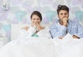 Young couple suffering from cold and flu in bed at home