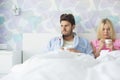 Young couple suffering from cold while relaxing in bed at home Royalty Free Stock Photo