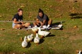 A young couple in summer clothes are sitting on picnic blanket on a sunny afternoon. They eat snacks and feed ducks