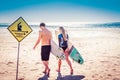 Young couple of surfers walking with there surfboards away from the photographer toward the sea past Strong Currents Royalty Free Stock Photo