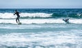 Young couple surfing with surfboard on waves in Atlantic ocean