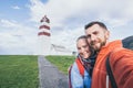 Young couple taking selfie with Alnes lighthouse on background. Godoy island, Norway