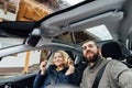 Young couple taking selfie in a car with glass roof