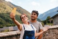 Young couple taking a selfie with mobile phone while doing rural tourism in a mountain village. Holiday trip and outdoor summer Royalty Free Stock Photo