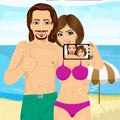 Young couple taking selfie photo together using smartphone camera at the beach and showing thumbs up Royalty Free Stock Photo