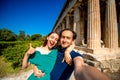 Young couple taking selfie picture with Hephaistos temple on background in Agora near Acropolis