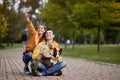 Young couple taking selfie with their dog in a lap, sitting on a path in park