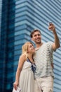 Young couple taking a selfie while touring a foreign city near skyscraper