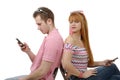 Young couple talking on mobile phones sitting back to back. Royalty Free Stock Photo