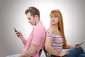Young couple talking on mobile phones sitting back to back. Royalty Free Stock Photo