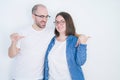 Young couple together wearing glasses over white  background pointing and showing with thumb up to the side with happy Royalty Free Stock Photo