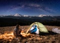 Young couple tourists having a rest in the camping at night under beautiful night sky full of stars and milky way Royalty Free Stock Photo
