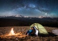 Young couple tourists having a rest in the camping at night under beautiful starry sky and milky way Royalty Free Stock Photo