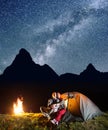 Young couple tourists looking to the shines starry sky and Milky way in the camping at night near campfire Royalty Free Stock Photo