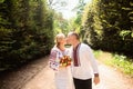 A young couple in a traditional Ukrainian clothing whith bouquet walking and kissing in the sunny park