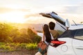 Young couple traveler with car watching a beautiful sunrise over the mountain while traveling road trip on vacation Royalty Free Stock Photo