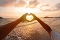Young couple traveler making heart shape with hands on the beach at sunset, Lovers on honeymoon Royalty Free Stock Photo
