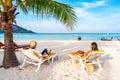 Young couple traveler relaxing and enjoying at beautiful tropical white sand beach with wave foam and transparent sea Royalty Free Stock Photo