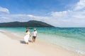 Young couple traveler relaxing and enjoying at beautiful tropical white sand beach with wave foam and transparent sea Royalty Free Stock Photo