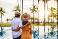 Young couple traveler relaxing and enjoying the sunset by a tropical resort pool while traveling for summer vacation Royalty Free Stock Photo