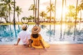 Young couple traveler relaxing and enjoying the sunset by a tropical resort pool while traveling for vacation Royalty Free Stock Photo